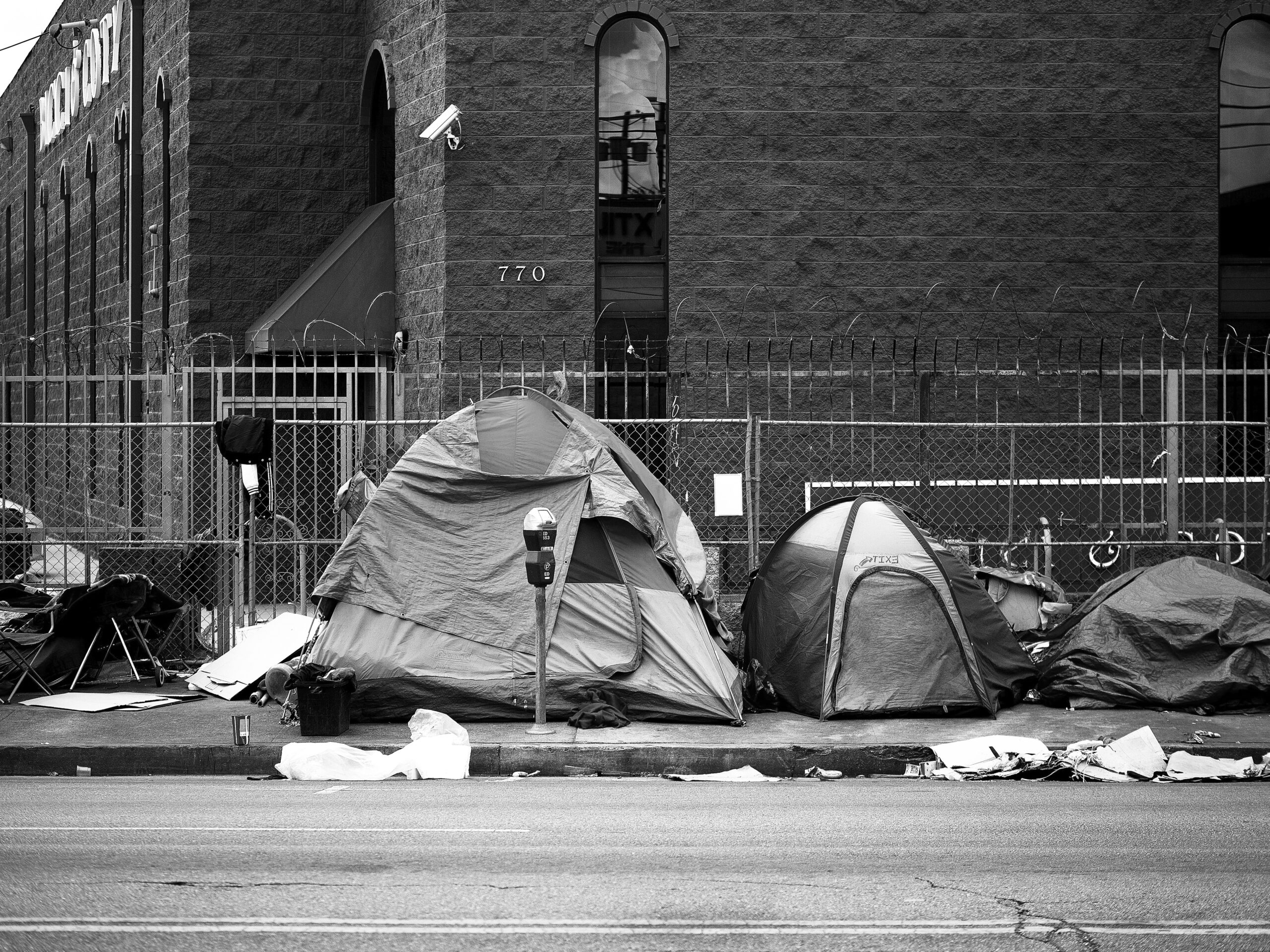 A row of tents on a sidewalk in an encampment for unhoused people.