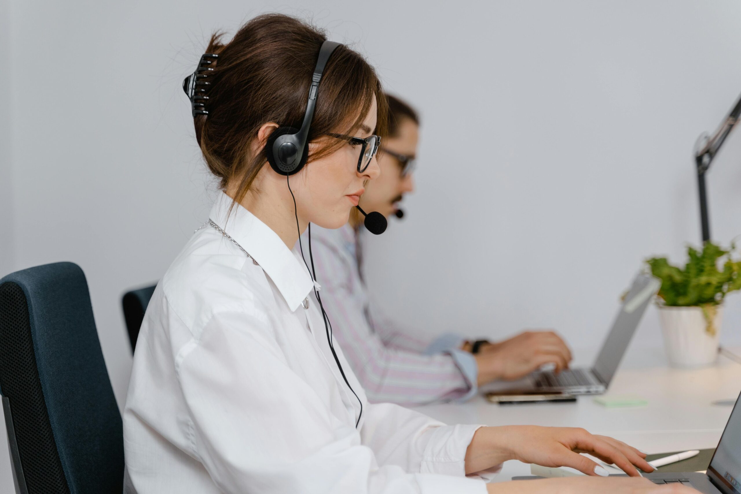 Side view of a woman wearing a headset and white shirt, working as a call center operator