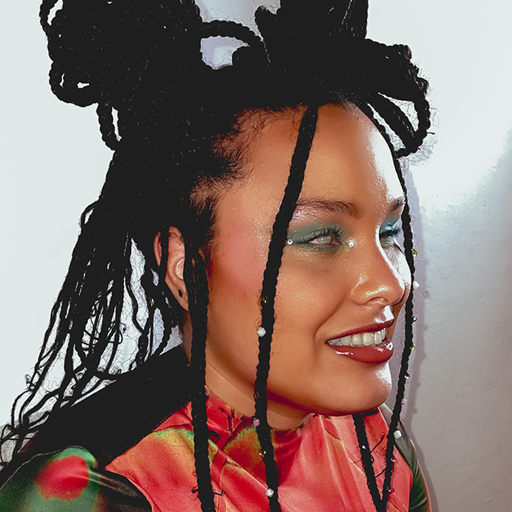 Previous Perez, an artists, stands in a red shirt with blue eye make up