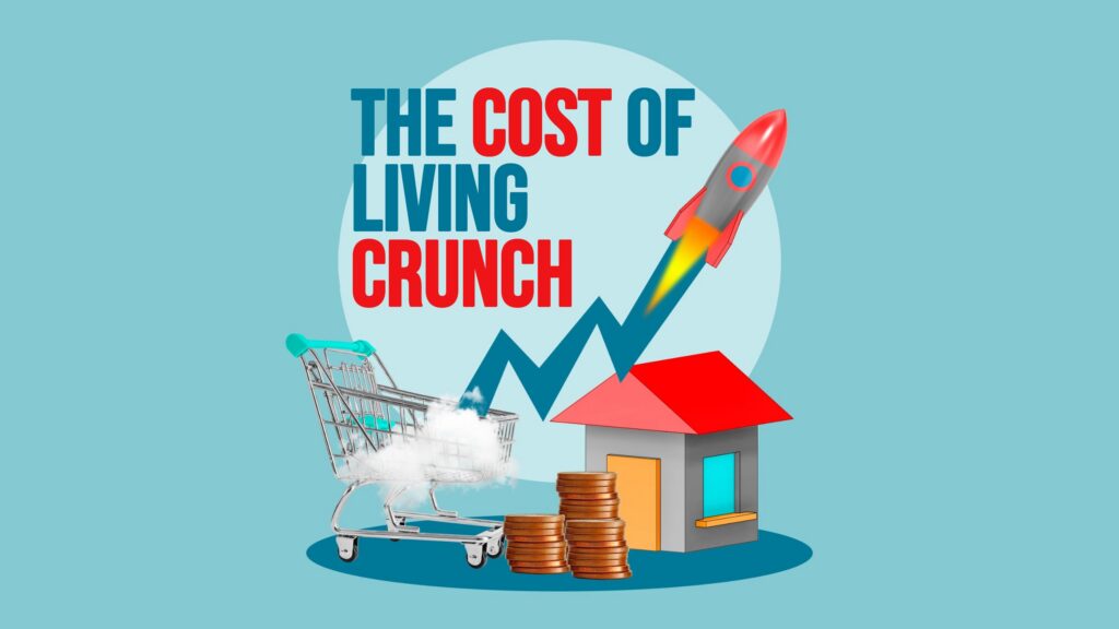 Illustration with the headline “The Cost of Living Crunch,” with “cost” and “crunch” in red. A zigzag line climbs from a shopping cart to a rocket blasting upward. Below are stacks of coins and a small house.